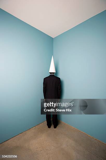 businessman wearing dunce cap - dunce cap stock pictures, royalty-free photos & images