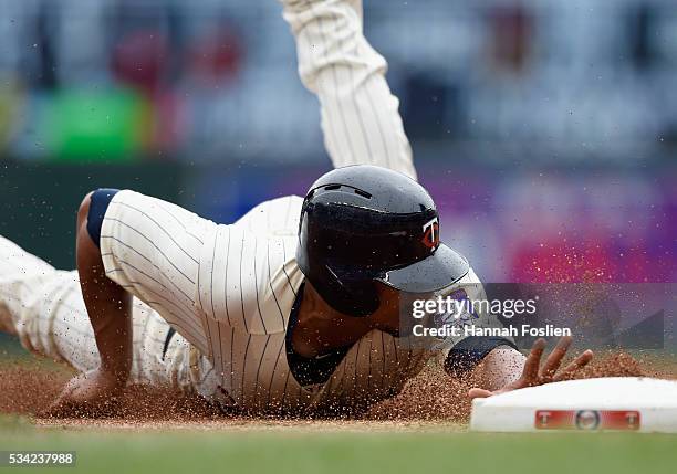 Eduardo Escobar of the Minnesota Twins slides safely into third base after a throwing error on a pick-off attempt at first base by Dillon Gee of the...