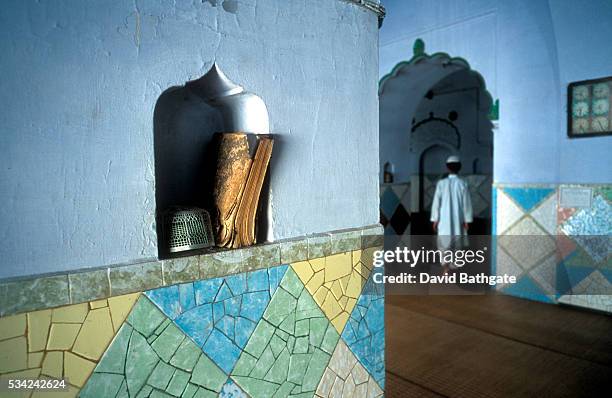 Young Muslim leaves a mosque near Darul-Uloom University after returning a Koran safely to its niche. | Location: Deoband, Uttar Pradesh, India.