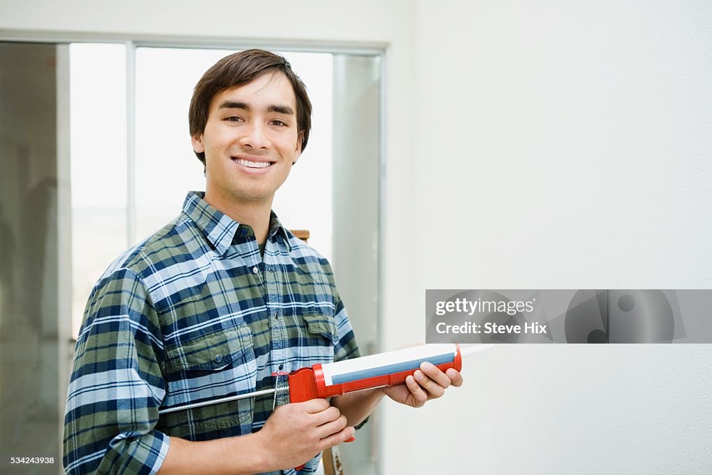 Man Holding Caulking Dispenser