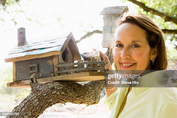 woman filling her bird feeder - bird feeder stock pictures, royalty-free photos & images