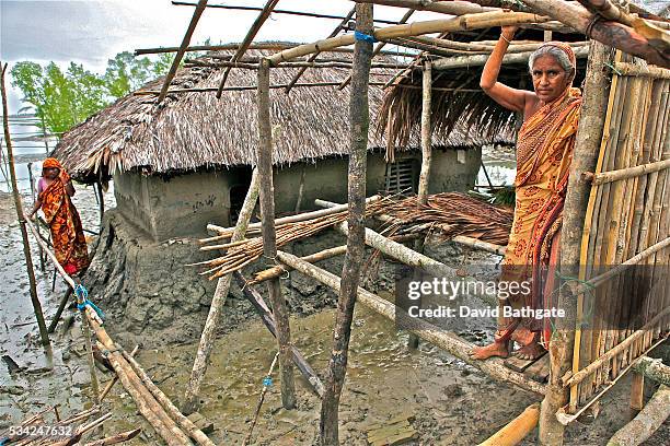 Village woman clings to new house construction on a narrow strip of higher ground in an area struck by Cyclone Aila on , triggering tidal surges,...