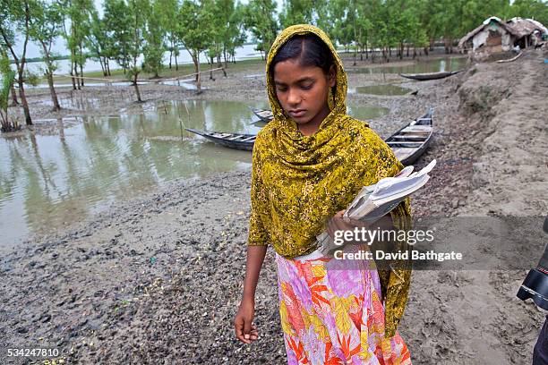 Village girl walks home from school along a narrow strip of higher ground in an area struck by Cyclone Aila on , triggering tidal surges, floods and...