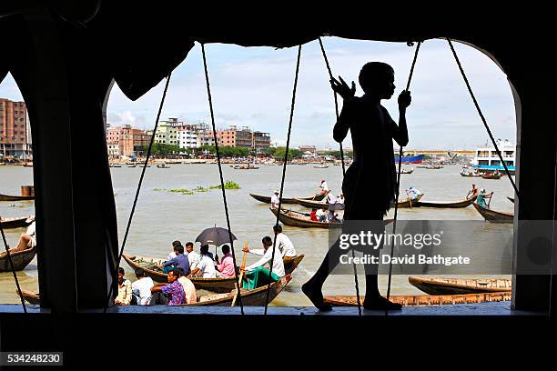 Boy walks along the side of a passenger ferry docked on the Buriganga River, near the Old City of Dhaka.