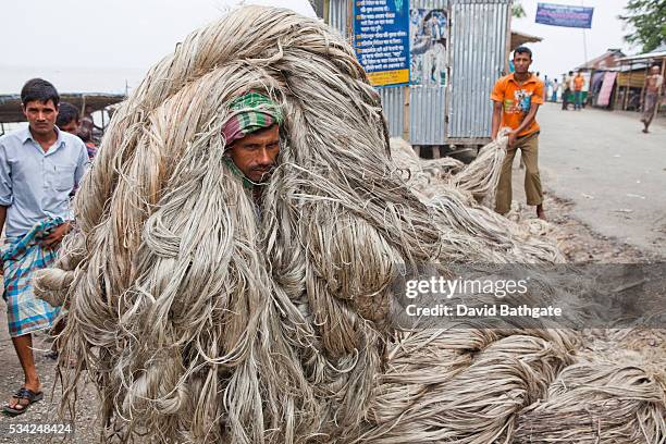 Day labourers unload raw jute fibers from a cargo boat. | Location: Char Bojradiarkhata, Bangladesh.