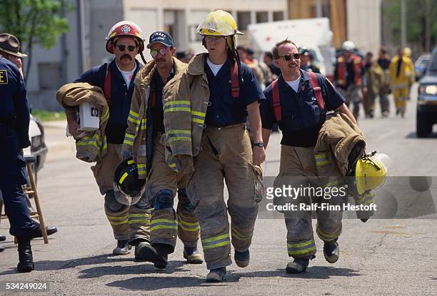 Weary firefighters and other rescue workers take a break from sifting through the rubble of the destroyed Federal Building in the aftermath of the...