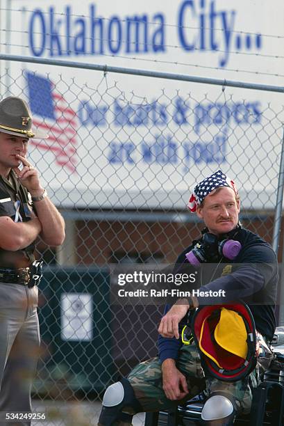 Weary rescue workers take a break after attempting to find survivors of the Oklahoma City bombing. A sign behind them reads "Oklahoma City...Our...