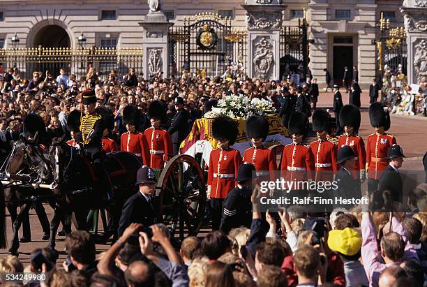 Mourners watch as the Queen's Life Guard escorts the coffin of Diana, Princess of Wales outside Buckingham Palace during her funeral.