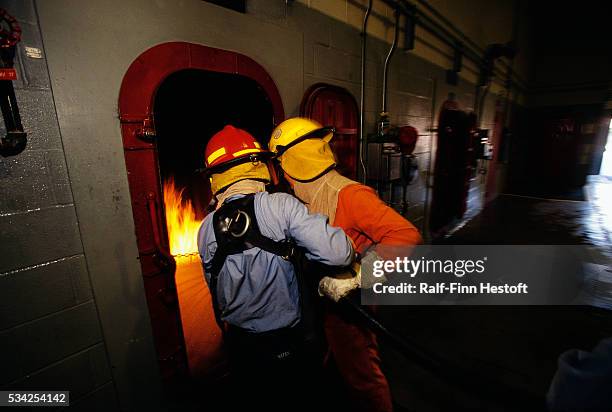 Navy recruits practice using a fire hose during firefighter training at the Great Lakes Naval Training Station in Illinois.