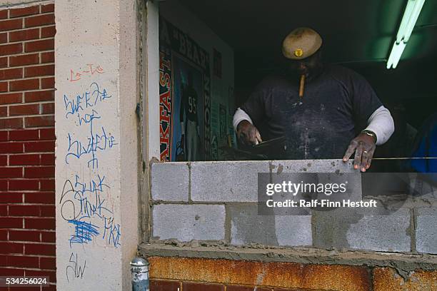 Bricklayer walls up an entrance at the Cabrini-Green housing project in Chicago. The construction workers are repairing a building in the housing...