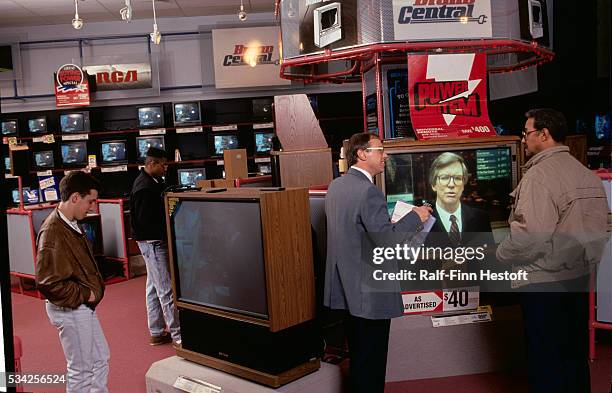 Shoppers looking at big screen television sets at a Sears Brand Central store. | Location: Woodfield, Illinois, USA.