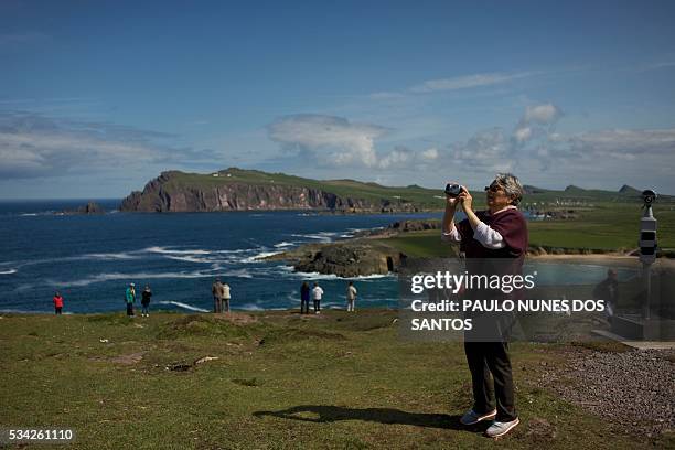 Tourists are pictured walking on a hilltop near the village of Ballyferriter on the scenic Dingle Peninsula in western Ireland, on May 23, 2016. The...