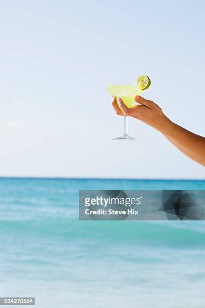 person holding margarita on beach - margarita beach stock-fotos und bilder