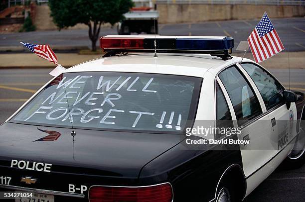 One month after the Oklahoma City bombing, a police car carries American flags and the words, "We Will Never Forget!!!" On April 19 Timothy McVeigh...