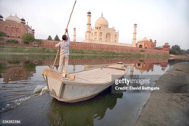 Boatman poles his way up the Yamuna River, on the Northern bank of the Taj Mahal.