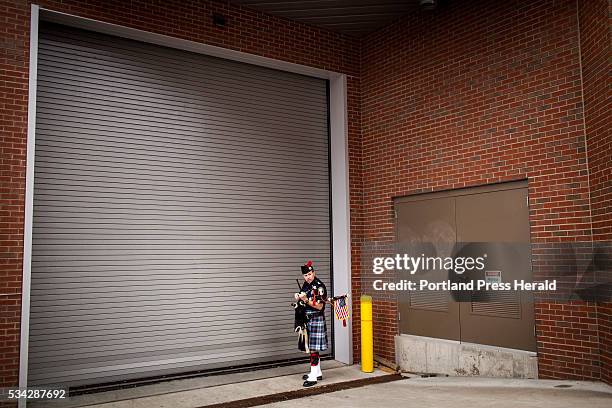 Brendan Murphy of Topsham, a bagpipe player with the Maine Public Safety Pipe & Drum Corps, adjusts his bagpipes outside a loading dock at the Cross...