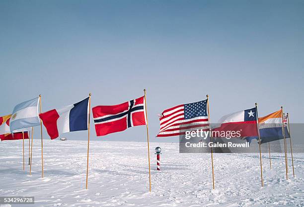 flags at the ceremonial south pole - antartide foto e immagini stock