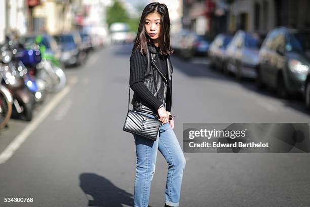 May Berthelot , is wearing an Iro sleeveless black leather jacket, The Kooples blue jeans, Zara black leather boots, a Chanel cachemire black body...