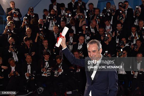 French director Olivier Assayas poses with his trophy during a photocall after he was awarded with the Best Director prize for the film "Personal...