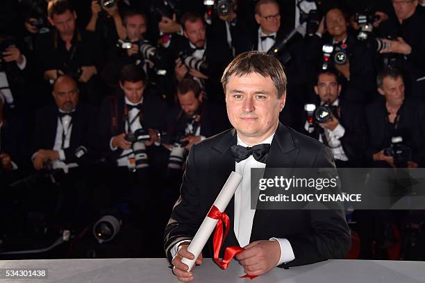 Romanian director Cristian Mungiu poses with his trophy during a photocall after he was awarded with the Best Director prize for the film "Graduation...