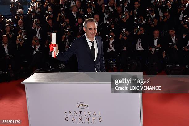 French director Olivier Assayas poses with his trophy during a photocall after he was awarded with the Best Director prize for the film "Personal...