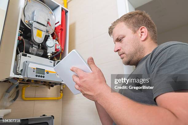 technicien réparation fourneau à l'aide de tablette numérique au gaz - boiler repair photos et images de collection