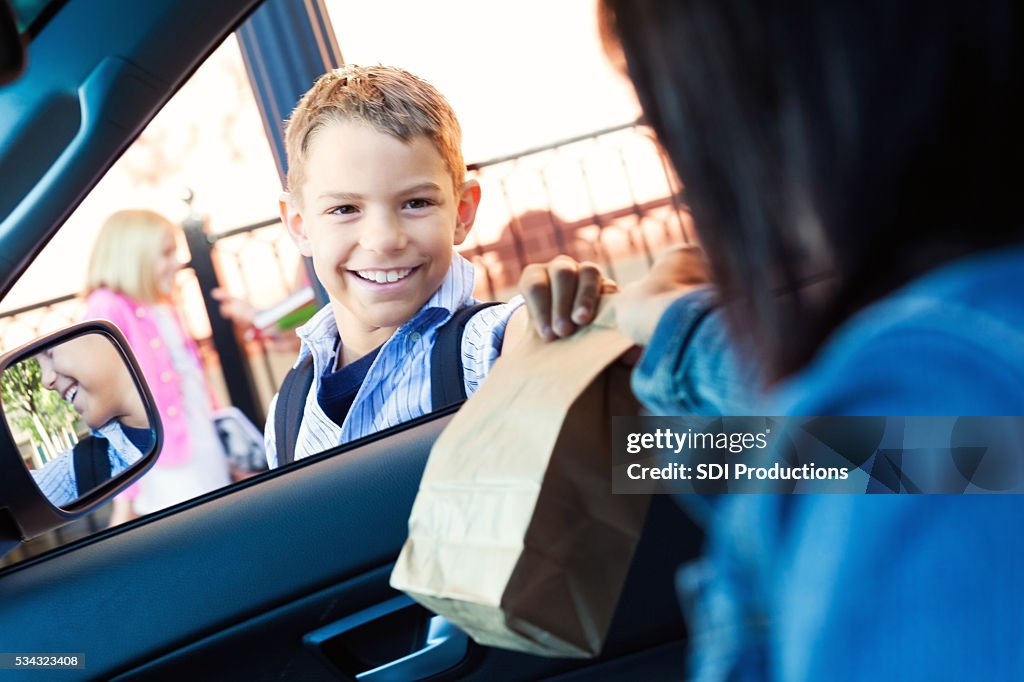 Mère donne fils son déjeuner en ligne à l’école carpool