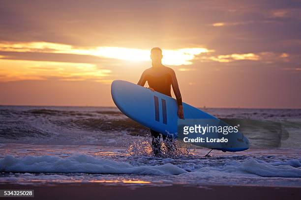 schöne mitte alter frau surfer am strand in der dämmerung - premium acess stock-fotos und bilder