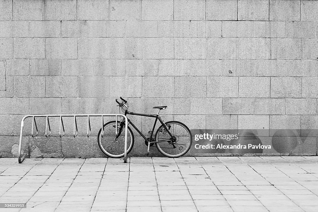 Bike parked in the street next to rack and wall