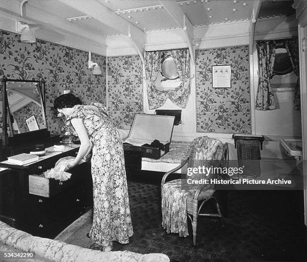Passenger unpacks her clothes in her stateroom aboard the RMS Ausonia.