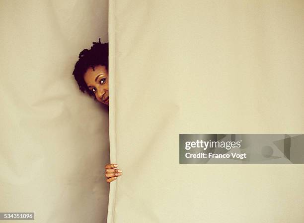 woman peeking from behind curtain - regarder à la dérobée photos et images de collection