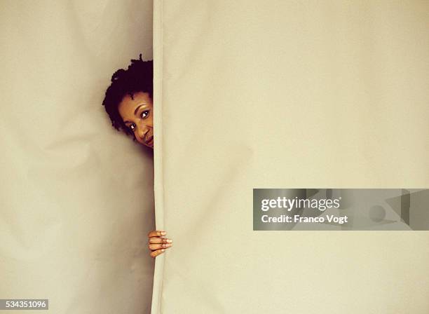 woman peeking from behind curtain - peeking through stock pictures, royalty-free photos & images