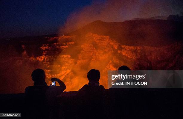 Tourists take pictures of a lava lake inside the crater of the Masaya Volcano in Masaya, some 30km from Managua on May 19, 2016. Hundreds of tourists...