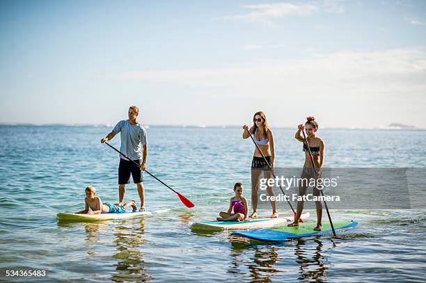 sup - stand up paddleboarding family - fat guy on beach stockfoto's en -beelden