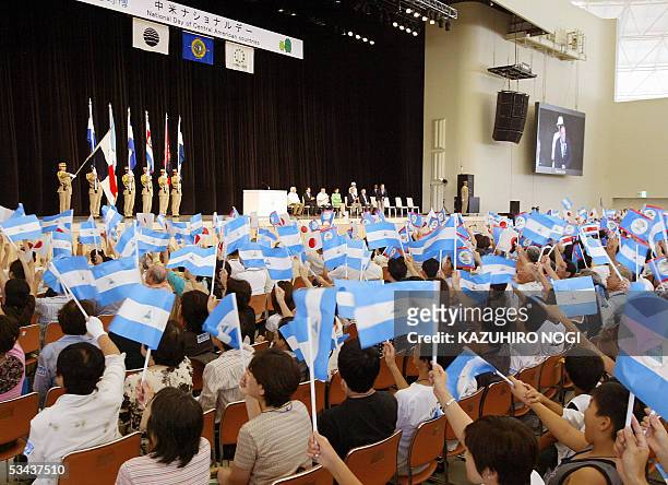 Mmebers of the audience wave Japanese and Central American countries' national flags at a ceremony of the Central America National Day for the 2005...