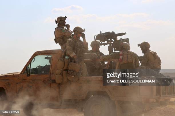 Armed men in uniform identified by Syrian Democratic forces as US special operations forces ride in the back of a pickup truck in the village of...