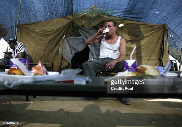 An Israeli border police officer has breakfast as another prays in the Reim army base on August 19, 2005 in the southern Gaza Strip. As Israel's...