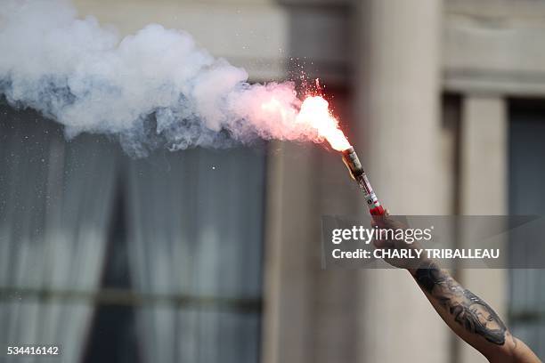 Man holds-up a flare a people demonstrate in Le Havre northwestern France, on May 26, 2016 to protest against the government's proposed labour...