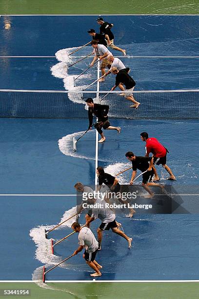 Grounds crew clear the court of water after torrential rains delayed the game between Amelie Mauresmo of France and Nadia Petrova of Russia during...