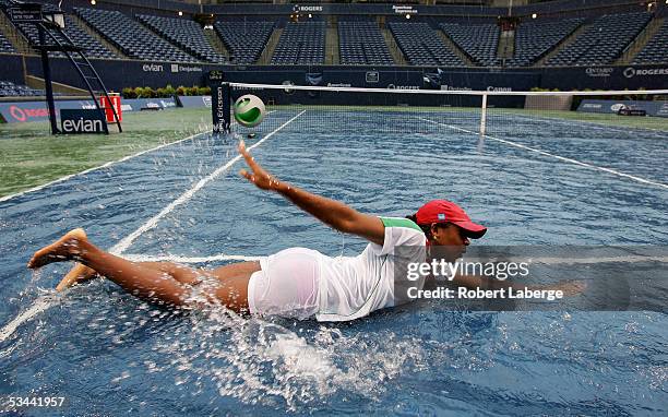 Ground crew worker Rachel Oryena pretends to swim in the water on center court after torrential rains delayed the game between Amelie Mauresmo of...