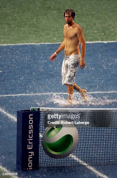 Ground crew member walks in the water on center court after torrential rains delayed the game between Amelie Mauresmo of France and Nadia Petrova of...