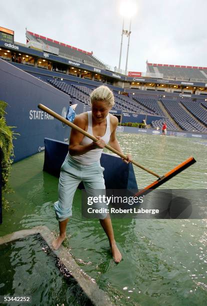 Kim Clijsters of Belgium plays with a squeegee on center court after torrential rains delayed play during the match between Amelie Mauresmo of France...
