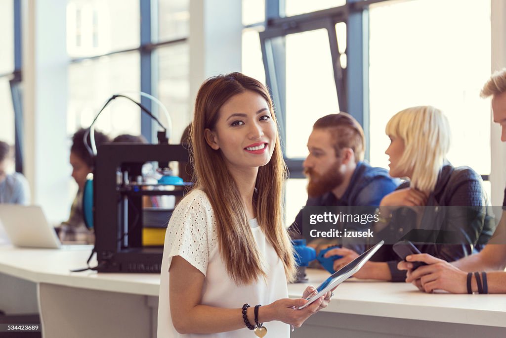 Young asian woman using digital tablet in 3D printer office