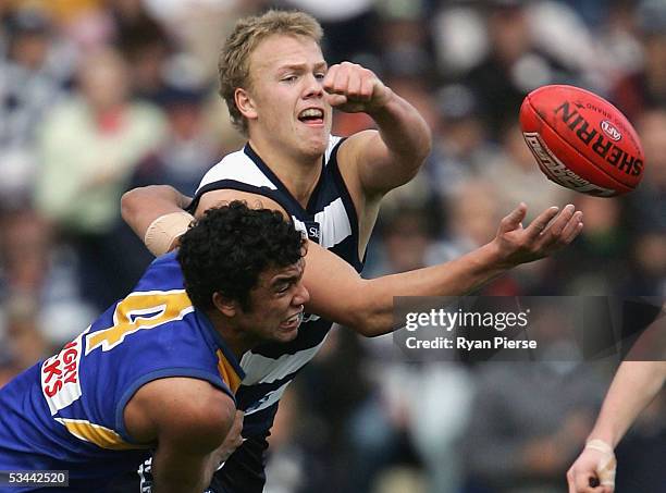 Nathan Ablett for the Cats handballs clear of Daniel Kerr for the Eagles during the round twenty one AFL match between the Geelong Cats and the West...