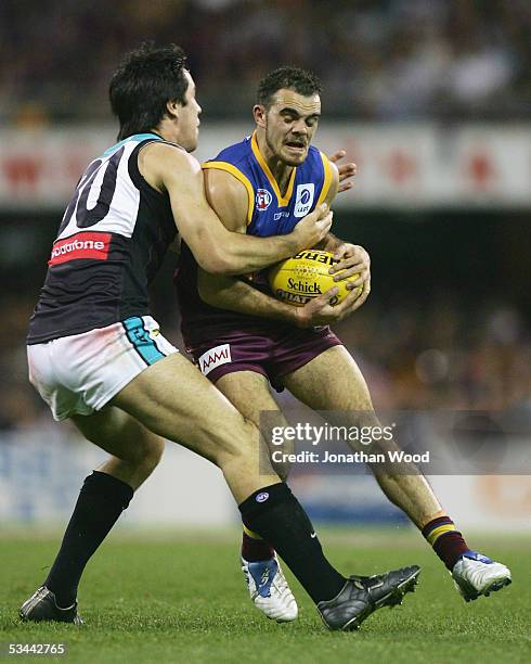 Ashley McGrath of the Lions is tackled by Troy Chaplin of Port during the AFL match between the Brisbane Lions and Port Adelaide at the Gabba on...