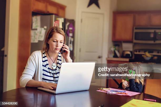 woman talking on phone while working with little girl copying her - working class mother stock pictures, royalty-free photos & images
