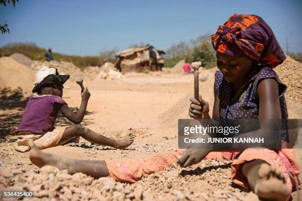 Child and a woman break rocks extracted from a cobalt mine at a copper quarry and cobalt pit in Lubumbashi on May 23, 2016. - The price of copper has...