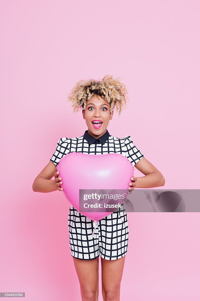 Afro American young woman holding pink heart shaped balloon