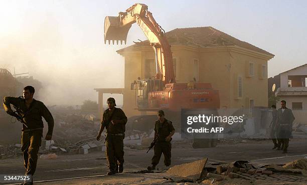 Israeli soldiers walk past a bulldozer demolishing a house in the Gaza Strip settlement of Peat Sade 21 August 2005. Israel's pullout from the Gaza...