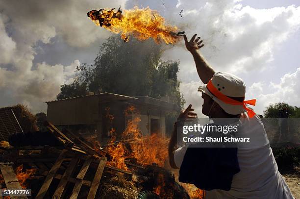 Settler thows debris on a fire August 21, 2005 at the Gaza Strip settlement of Katif. Israel neared the completion of its disengagement with the...